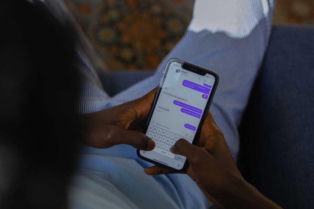 Close-up of hands holding a smartphone and typing a message on the touch screen.