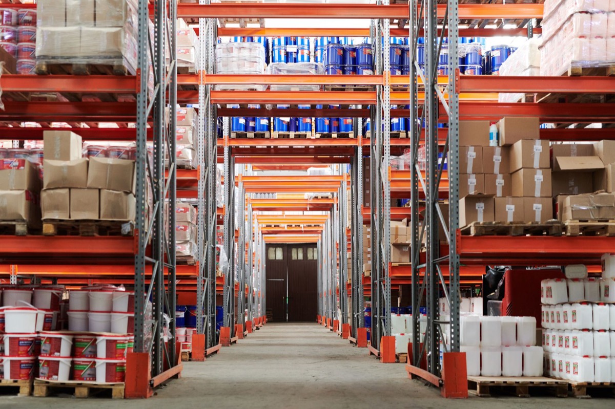 A wide angle view of a warehouse with stocked shelves and boxes.