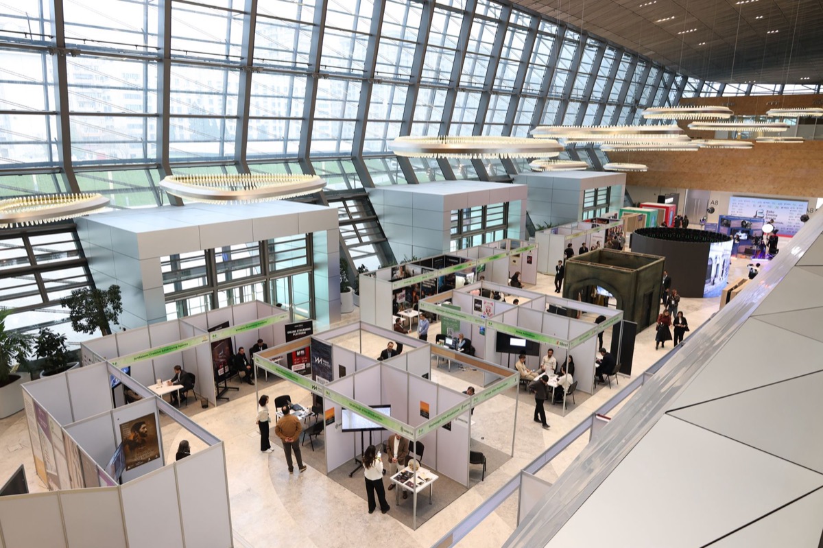 A bustling trade show exhibition inside a modern hall with attendees networking.