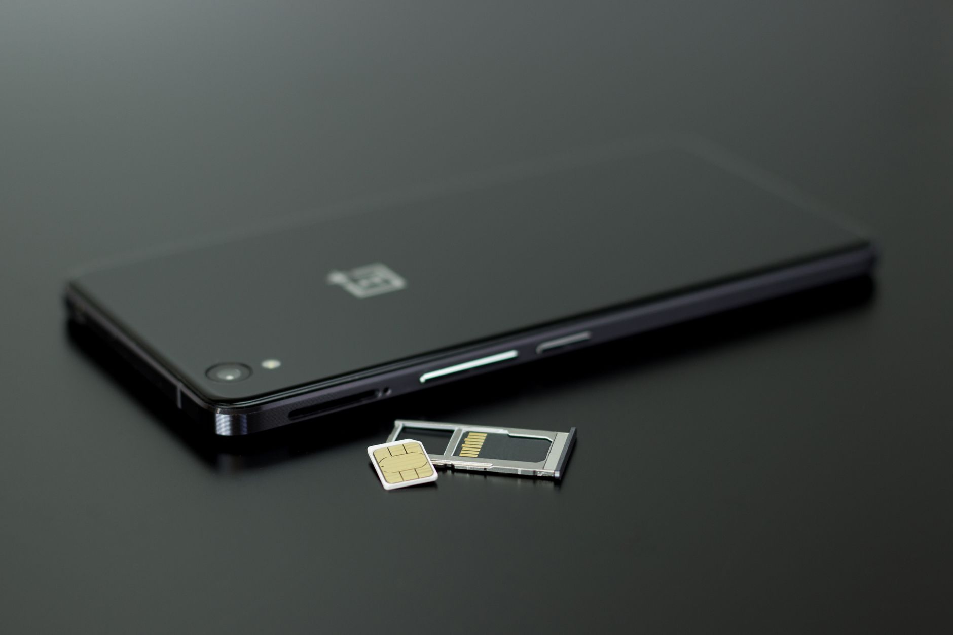 Close-up of a smartphone beside a SIM card and ejector tool.