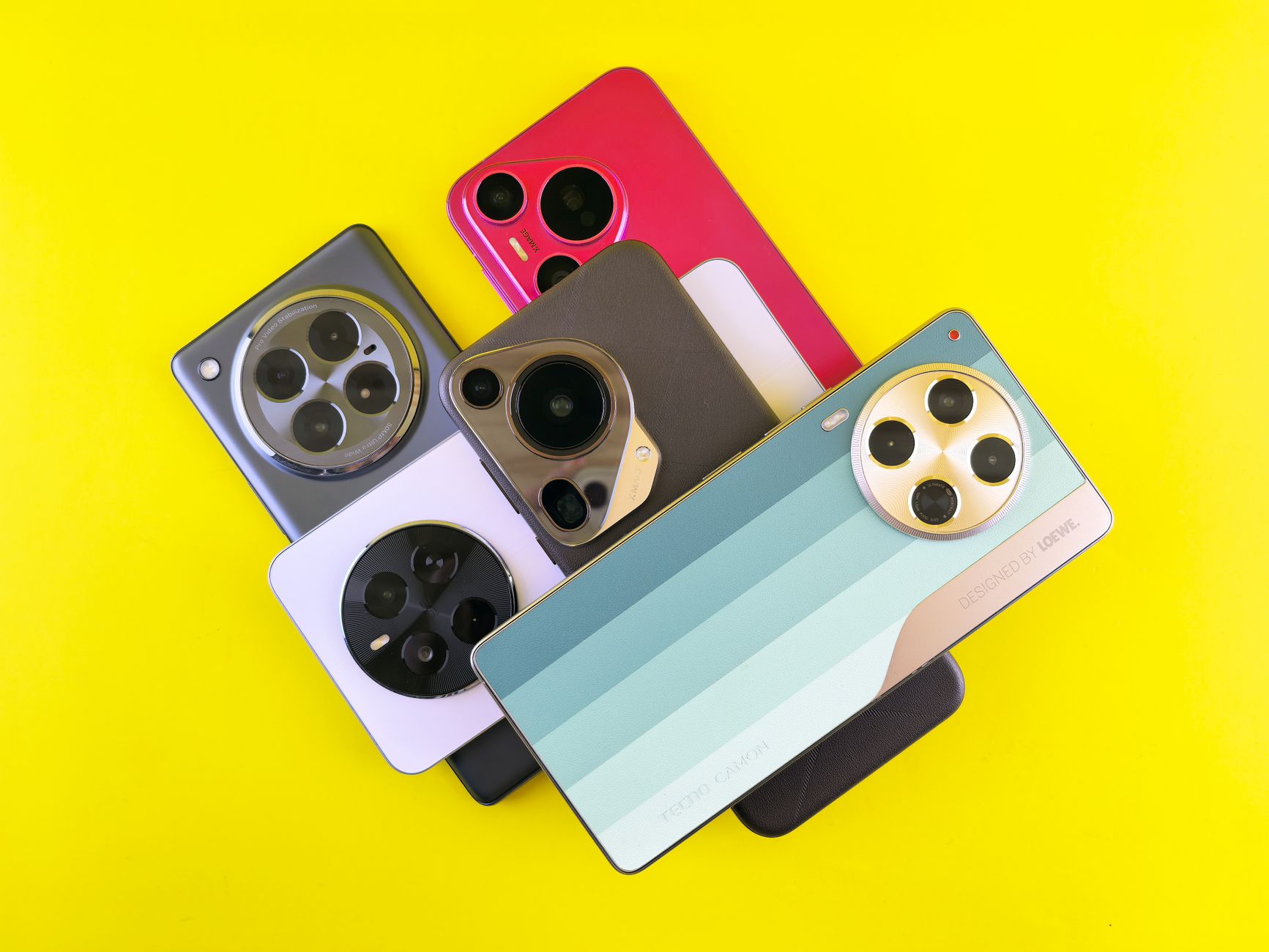 A collection of diverse smartphones laid out on a yellow backdrop.