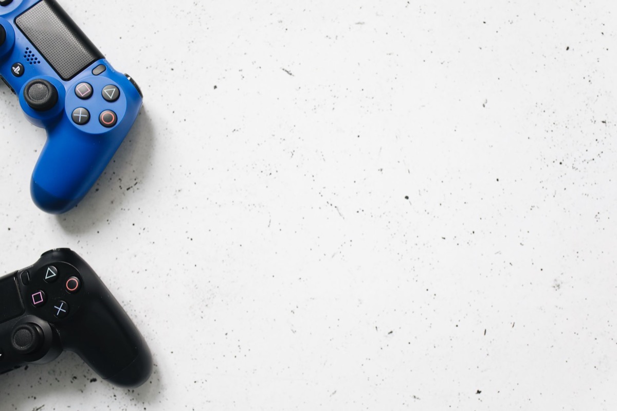 Blue and black game controllers arranged on a minimal white surface.