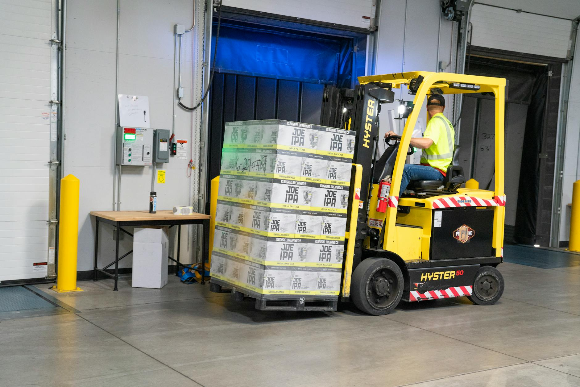 Warehouse workers operating a forklift among storage shelves, illustrating mobile-phone distribution operations.