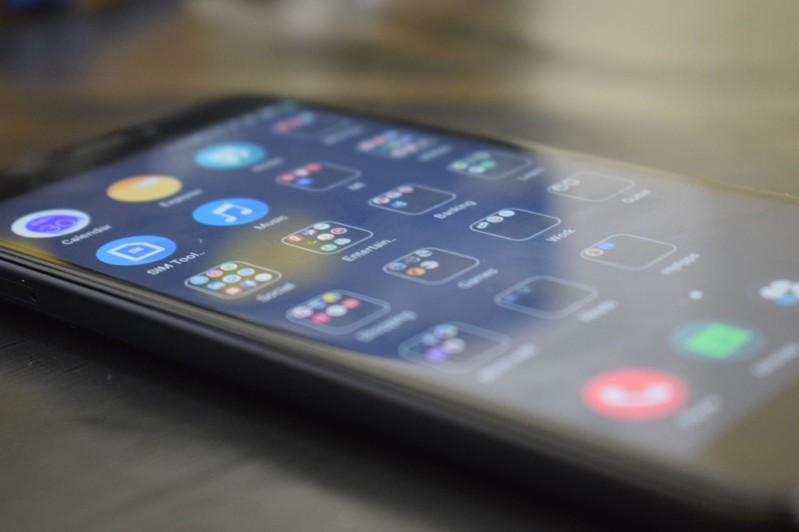 Close-up of a smartphone lying on a table, its app home screen viewed at an angle.
