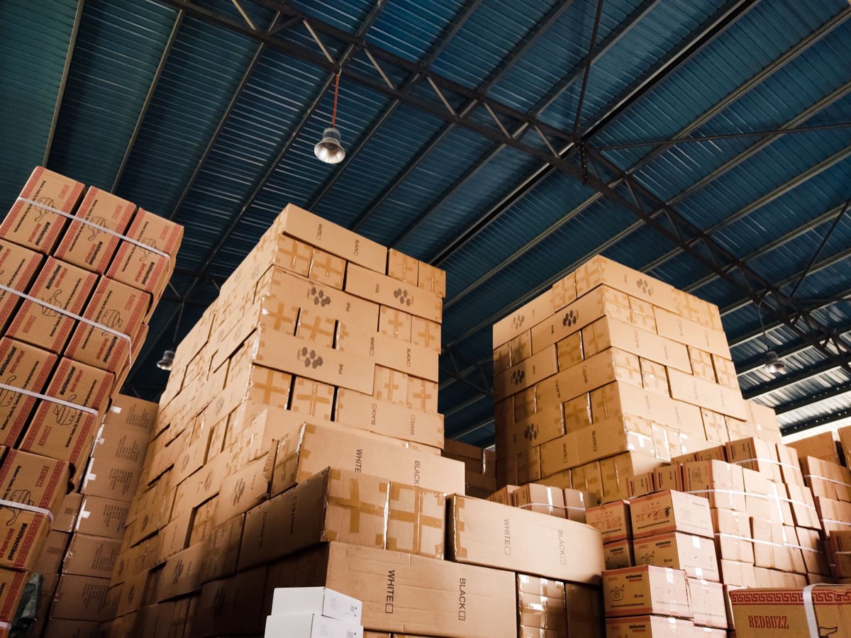 High stacks of cardboard boxes organized in a warehouse with a metal ceiling.
