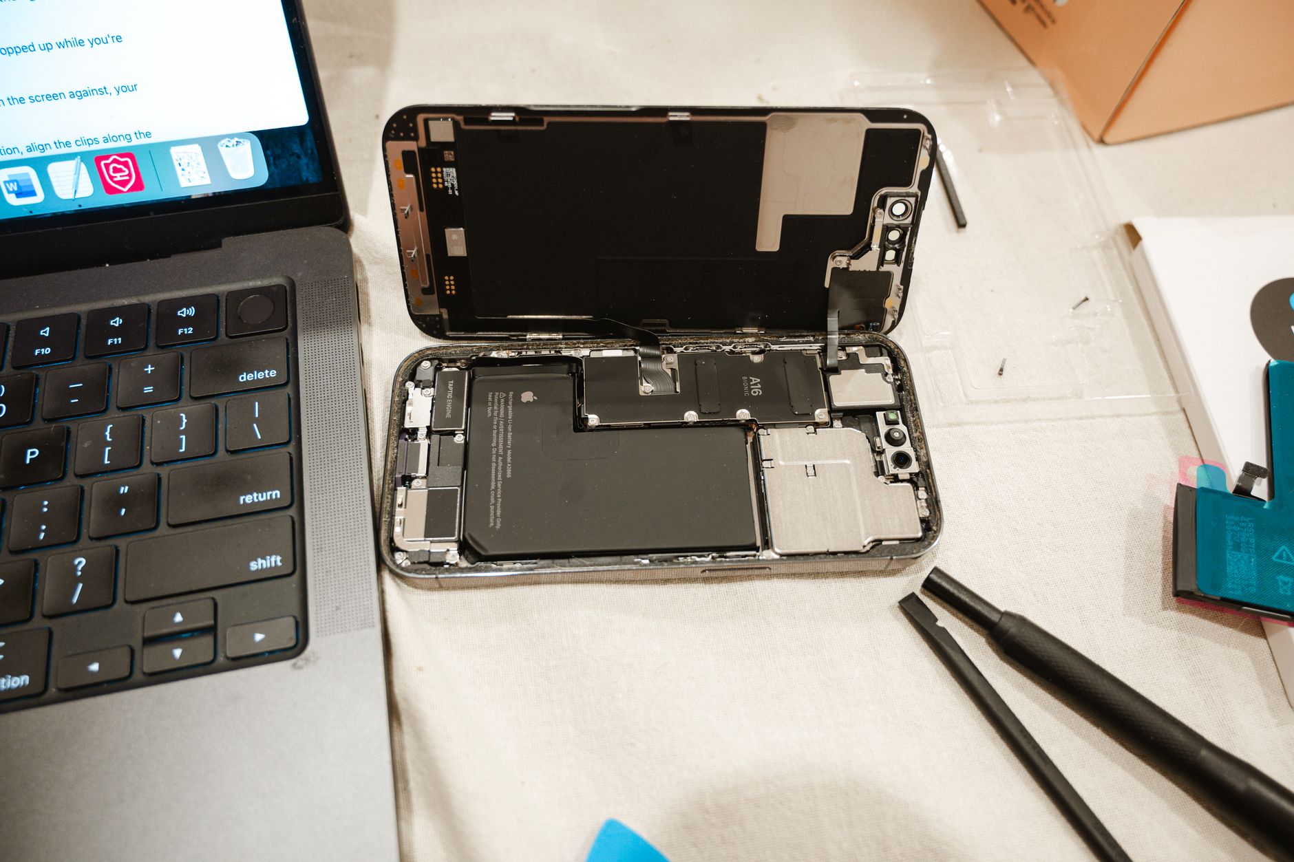 An opened iPhone on a repair bench with tools beside it.