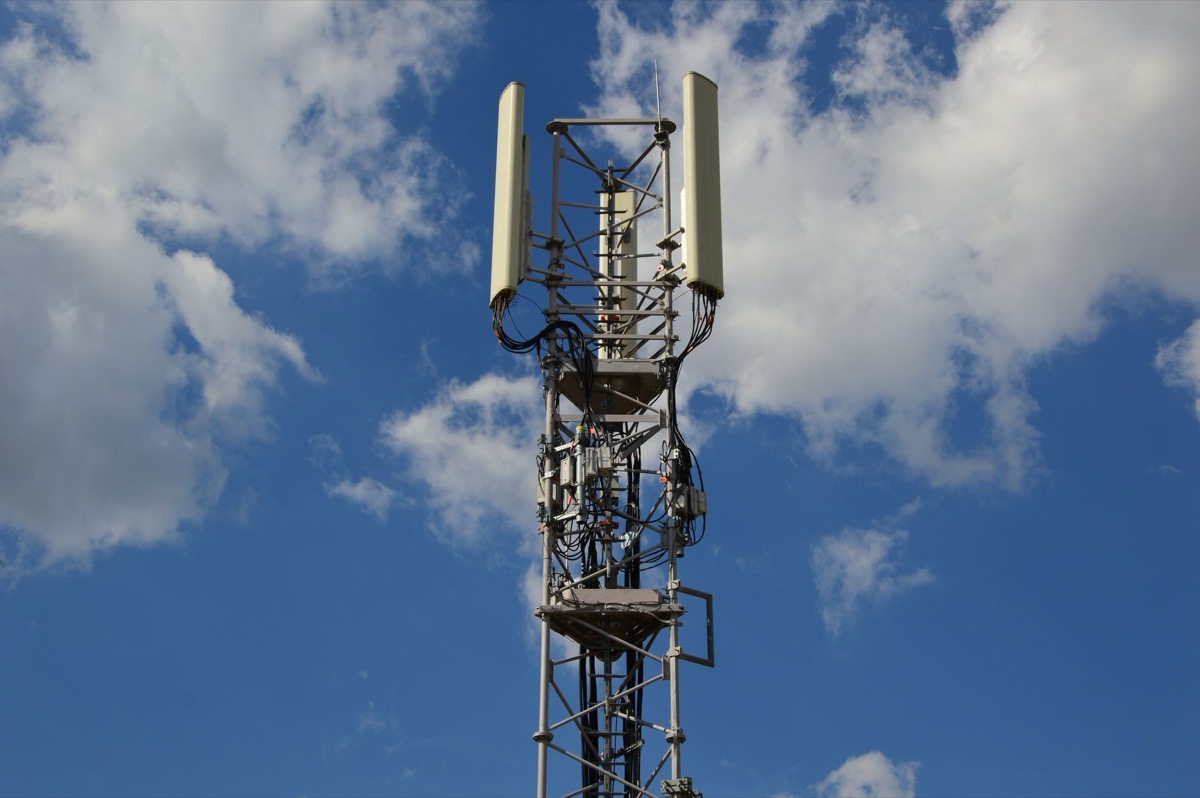 A tall cellular communication tower against a vivid blue sky.