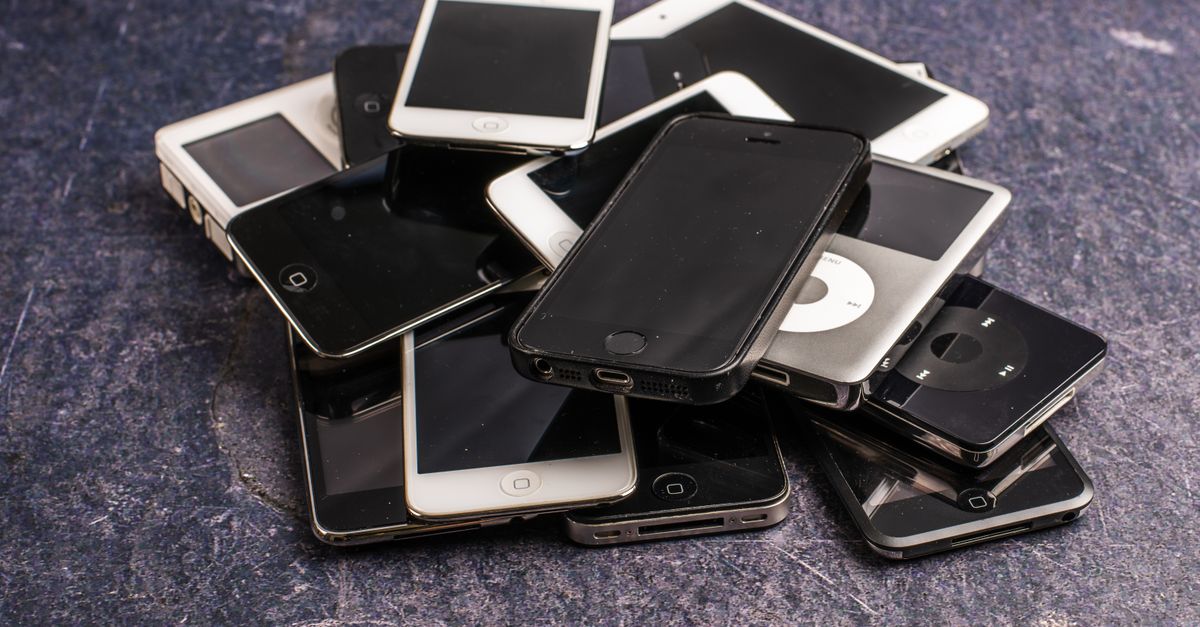 A stack of used phones and portable media players awaiting resale.