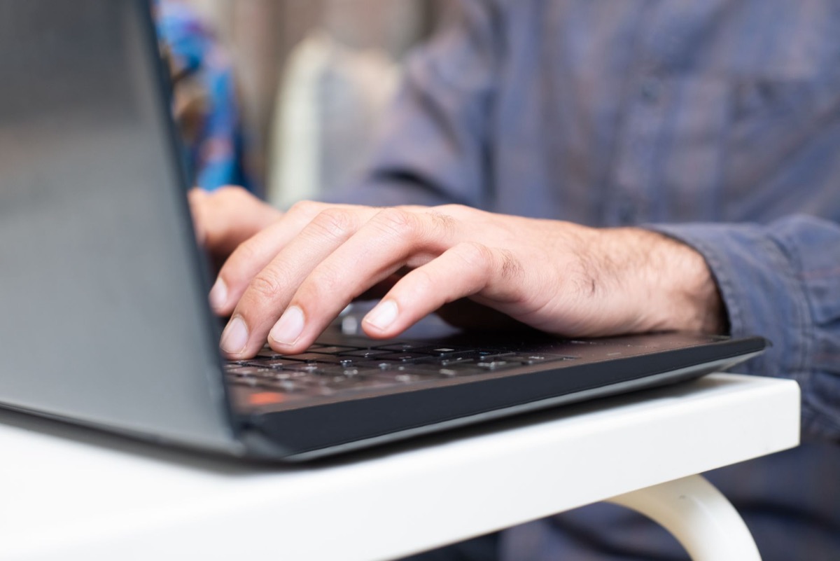Close-up of hands typing on a laptop keyboard in a professional setting.