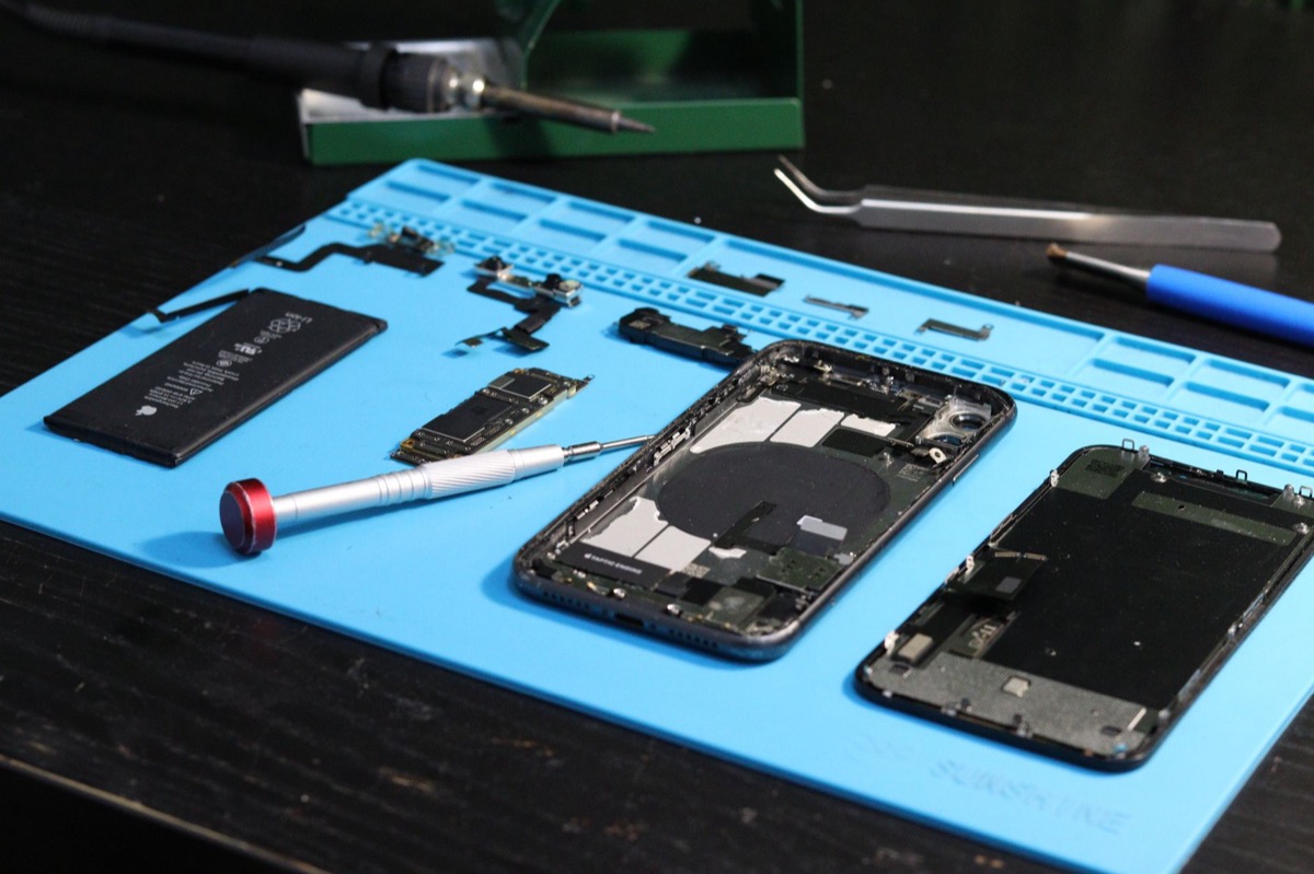 Close-up of disassembled smartphone parts on a repair mat with tools.