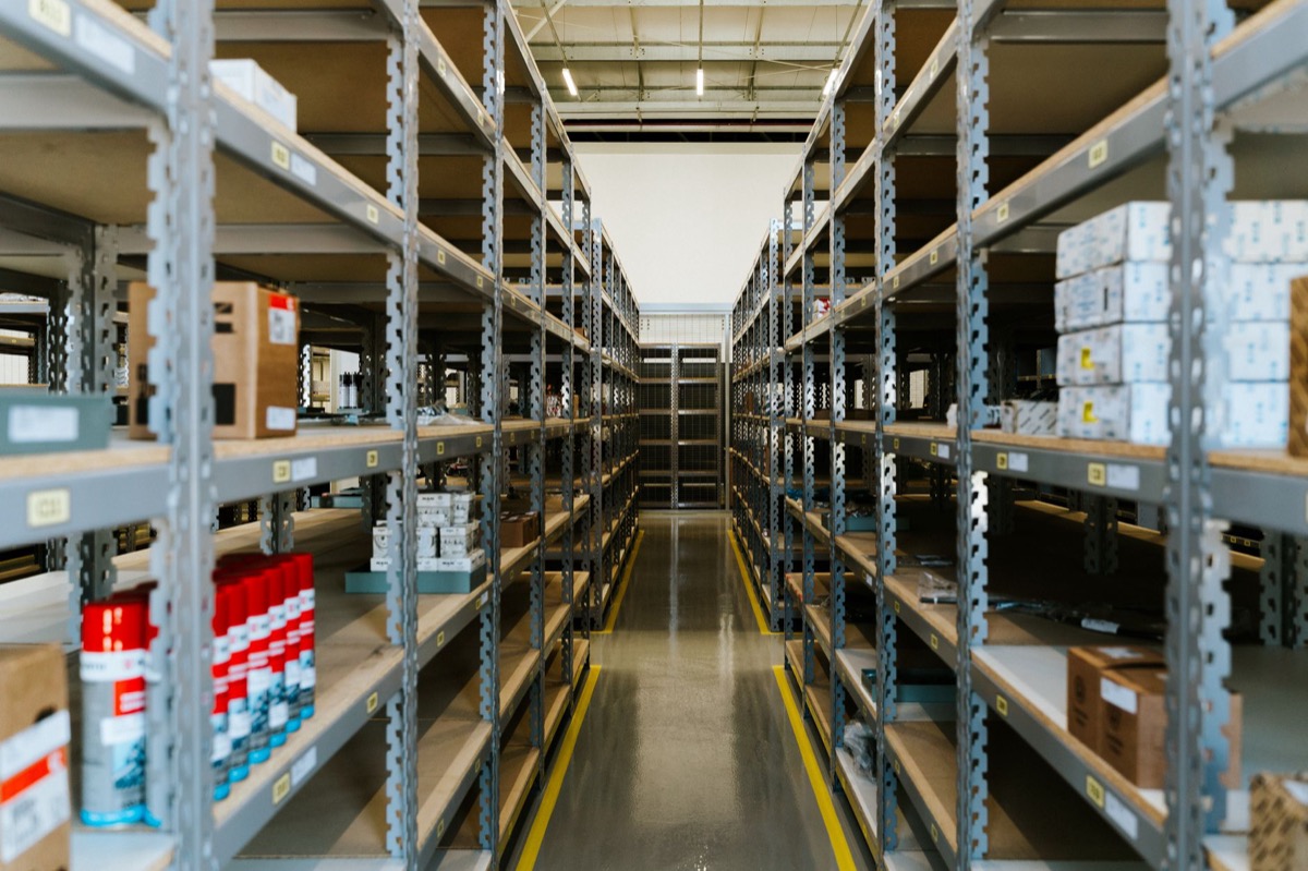 A wide view of an organized industrial warehouse with metal shelving and stored merchandise.