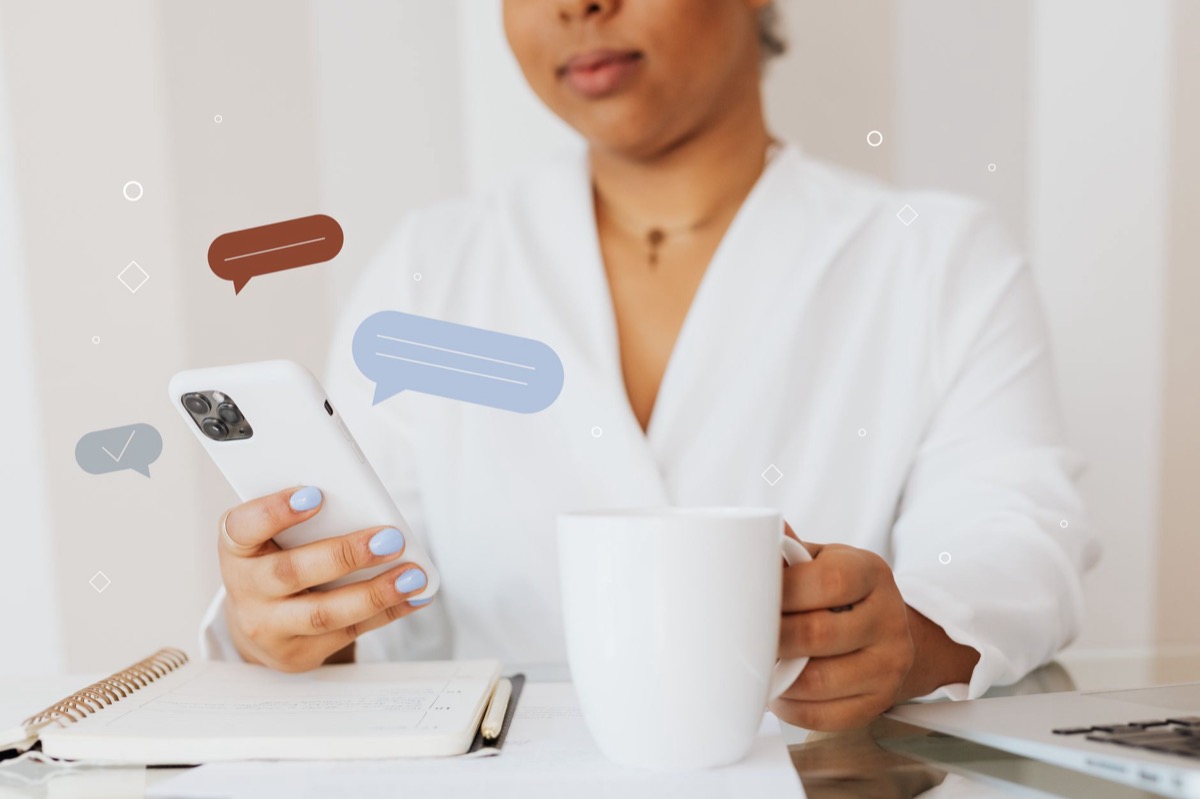 Close-up of a person using a smartphone while holding a coffee cup.