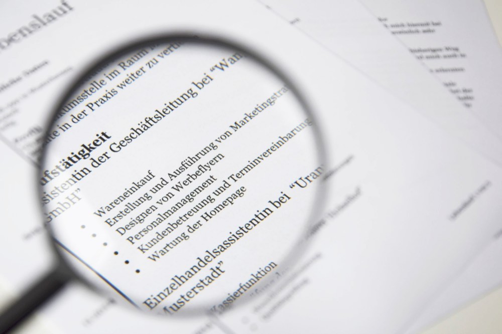 Close-up of a business document under a magnifying glass, representing fraud and scam investigation.