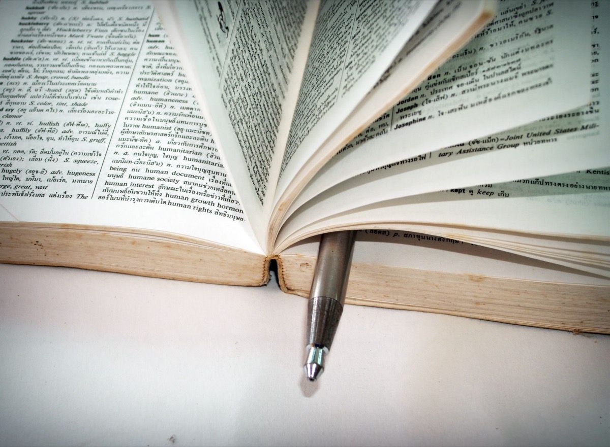A close-up of an open dictionary with a pen separating the pages.